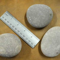 multiple medium hammerstones with ruler for scale